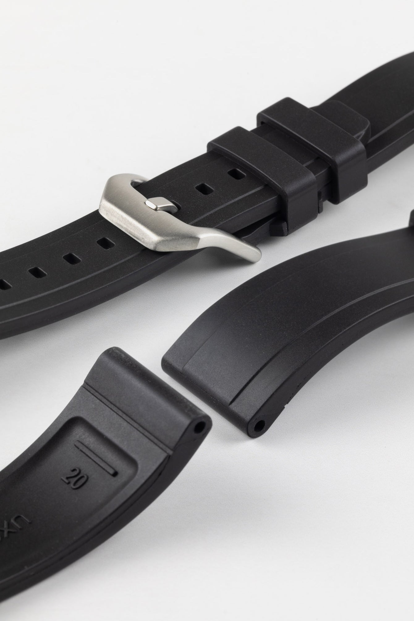 Product photo on the UX03 Rubber FKM watch strap showing the buckle done up in brushed steel, next to the underside of the strap showing the lug holes and curved fitting for comfort