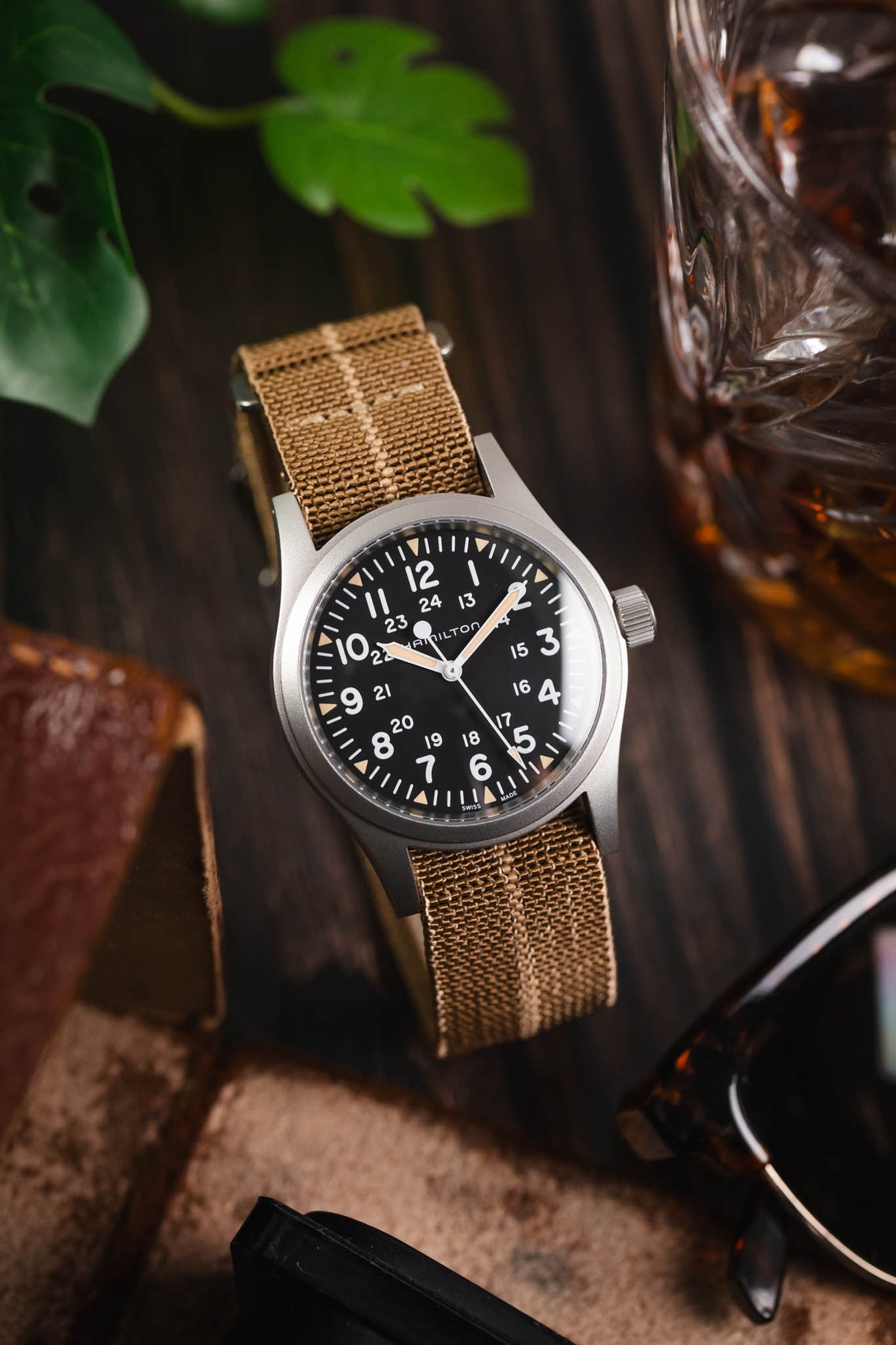 Hamilton watch on a wooden table fitted to a brown parachute webbing watch strap with brushed stainless steel hardware