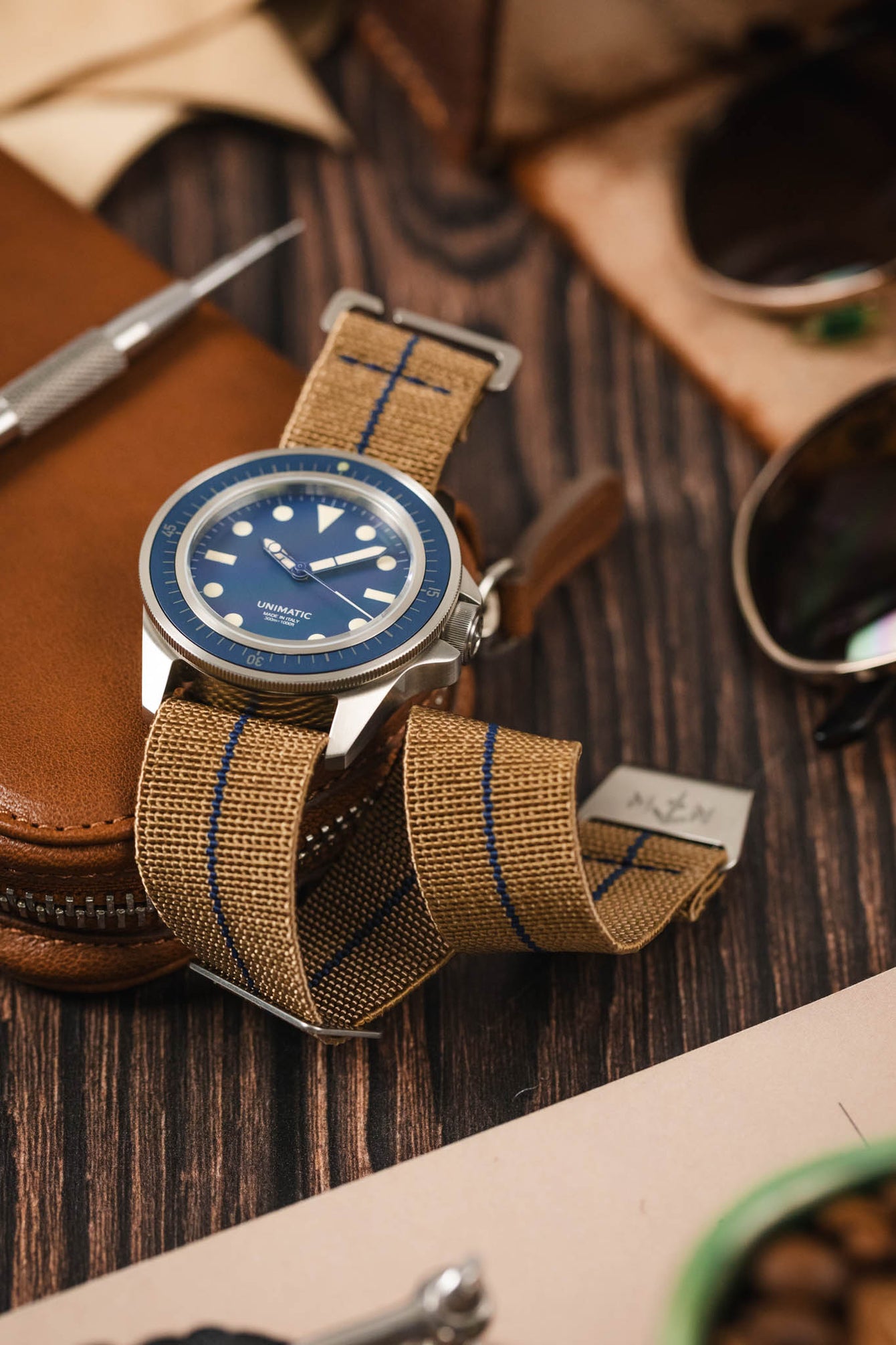 A curved webbing strap showing the flexibility and comfort of the strap, it has a blue centerline matching the blue dial of the watch.