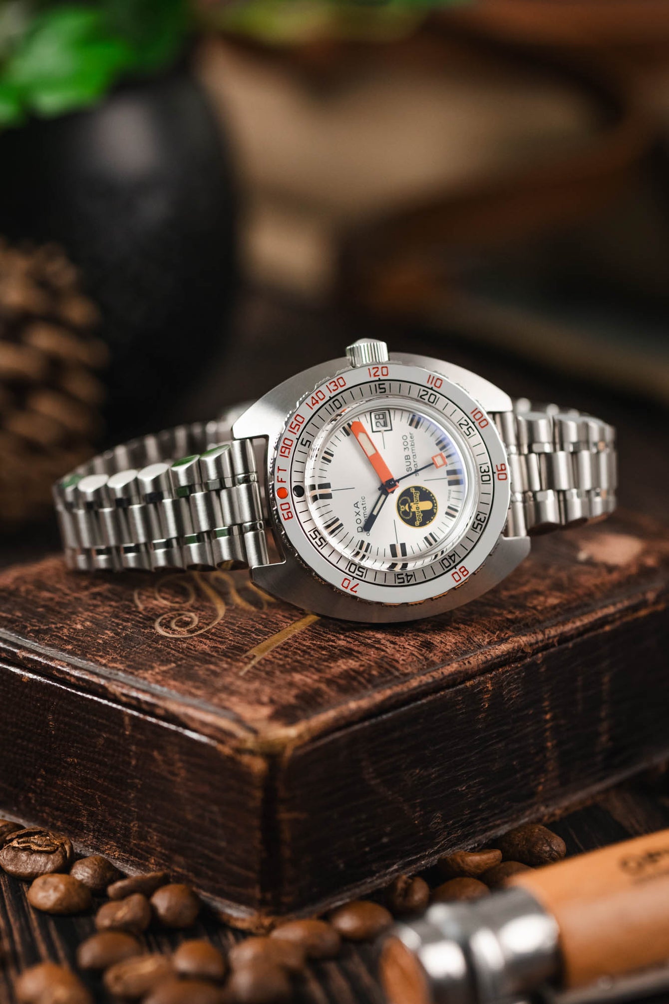 Doxa Sub 300 Watch fitted to Forstner Bullet Bracelet lay on a leather box with coffee beans, knife in a moody scene