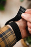 A close-up showing the adjustment of a black fabric watch strap with VELCRO closures on a person's wrist, illustrating the ease of use and adjustable fit of the strap.