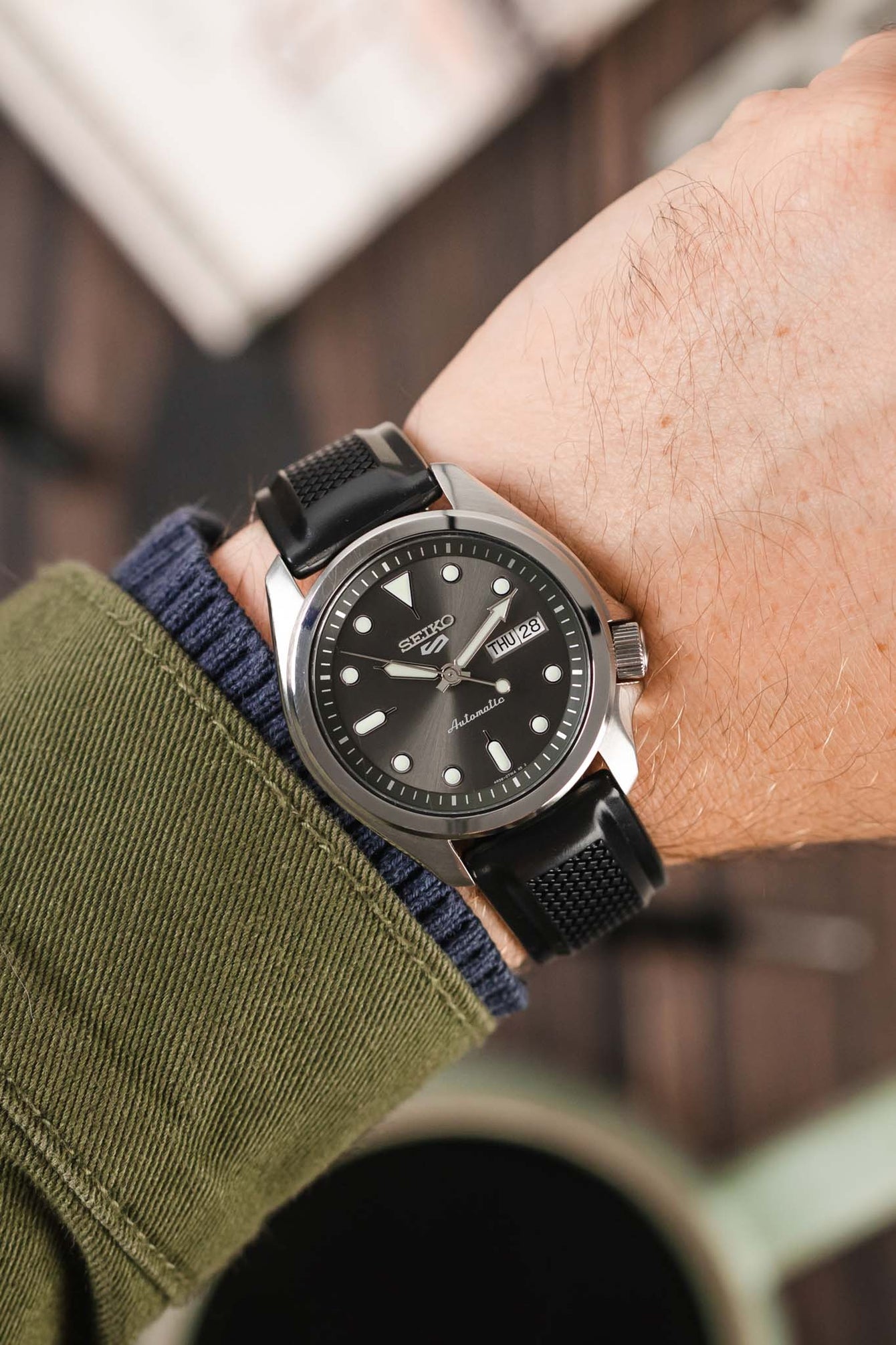 Seiko 5 Sports Anthracite dial fitted with Hirsch Accent Rubber Strap in Black on wrist with green shirt